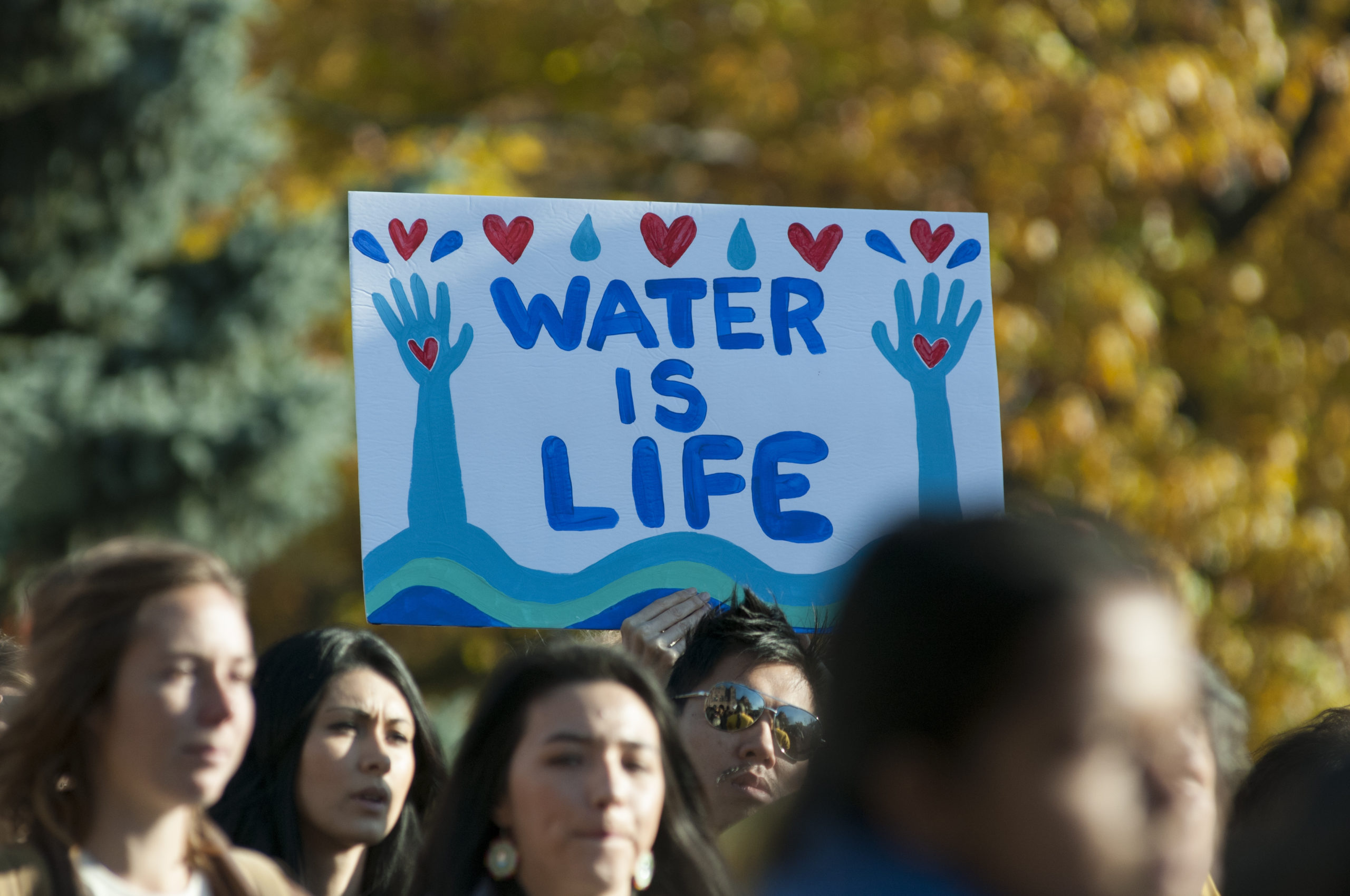People holding a sign that says "Water Is Life." Photo by arindambanerjee