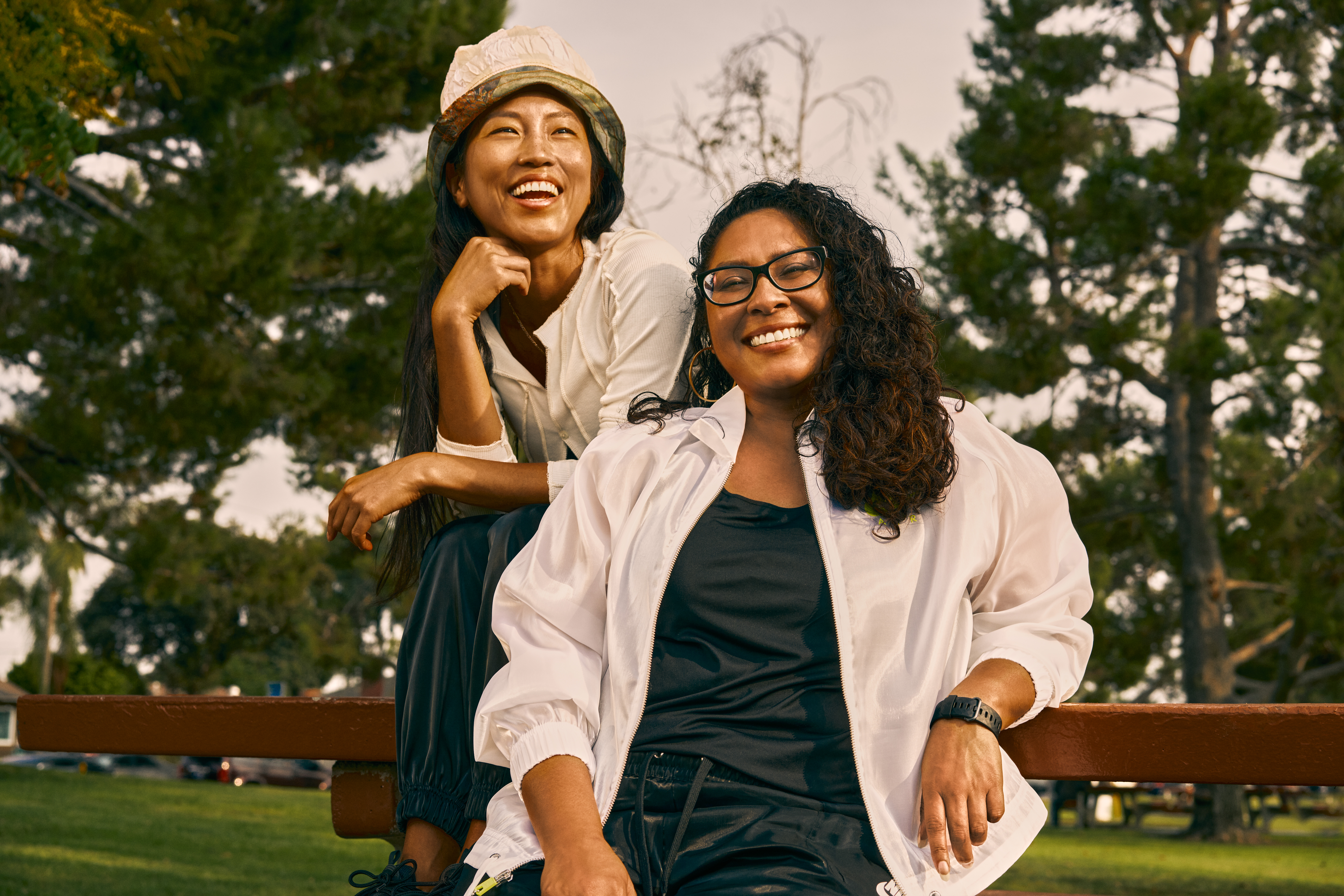 An Asian woman and a Latina woman hang out in a park. Photo by TONL. 