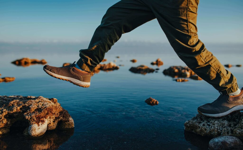 Boy walking on stones in the lake close-up view